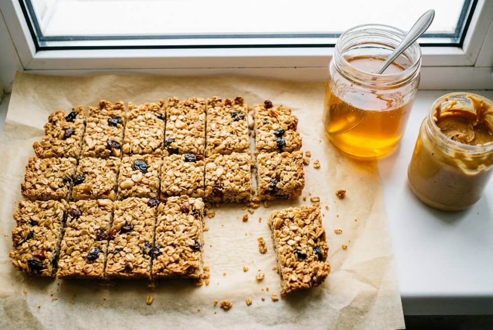 Pokrojone batony owsiane z bakaliami na papierze do pieczenia.