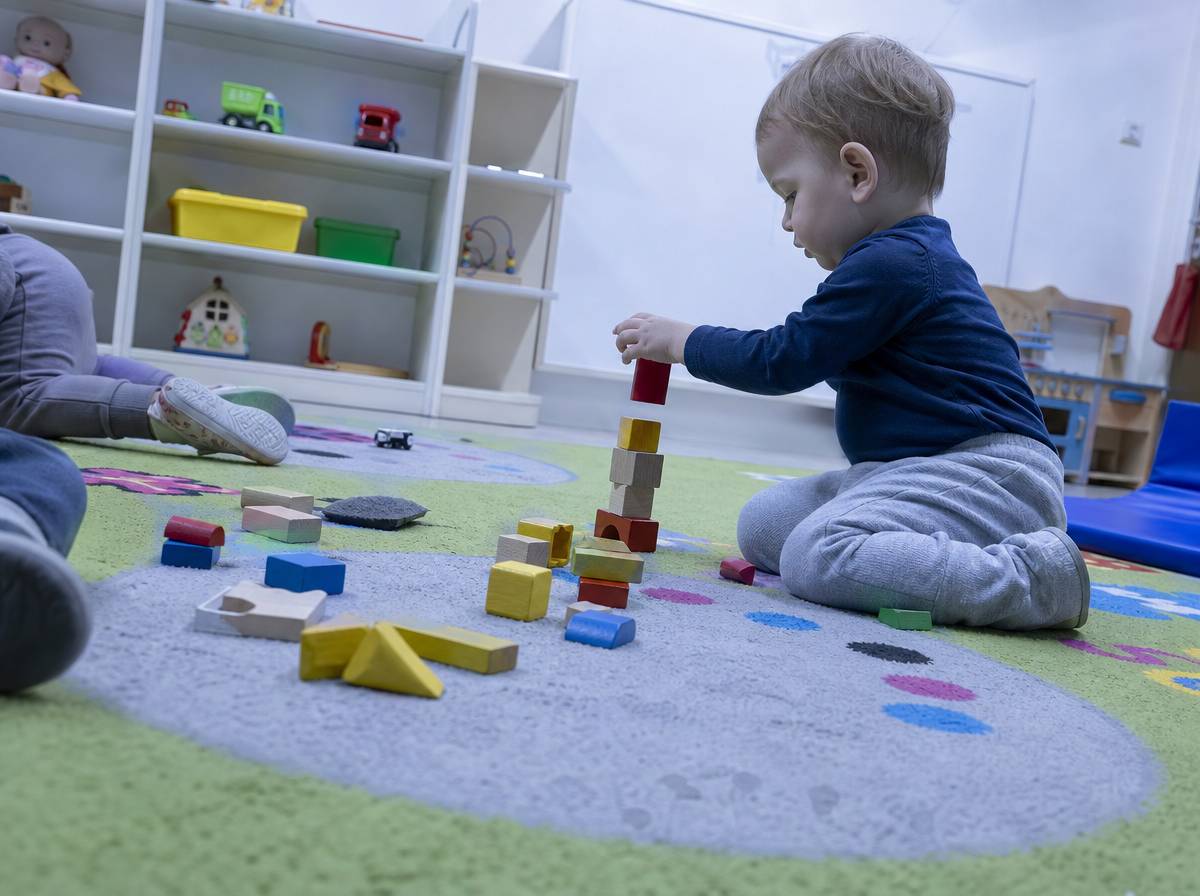 Dziecko samodzielnie bawi się klockami w sali żłobka po udanej adaptacji