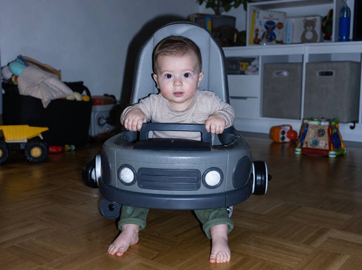 Niemowlę w jeździku-samochodziku z wysokim oparciem i barierką z przodu