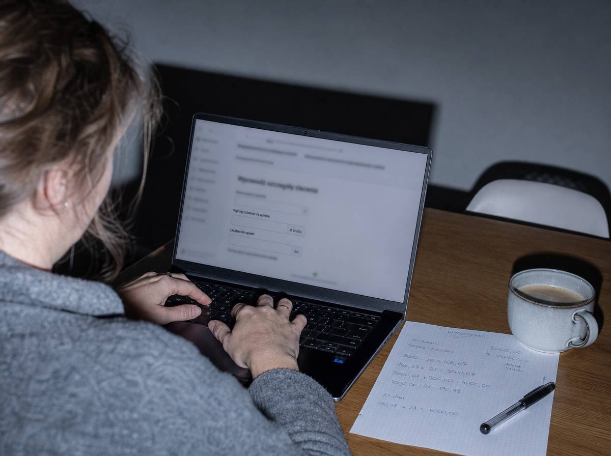 Kobieta wpisuje dane do kalkulatora zasiłku opiekuńczego na laptopie
